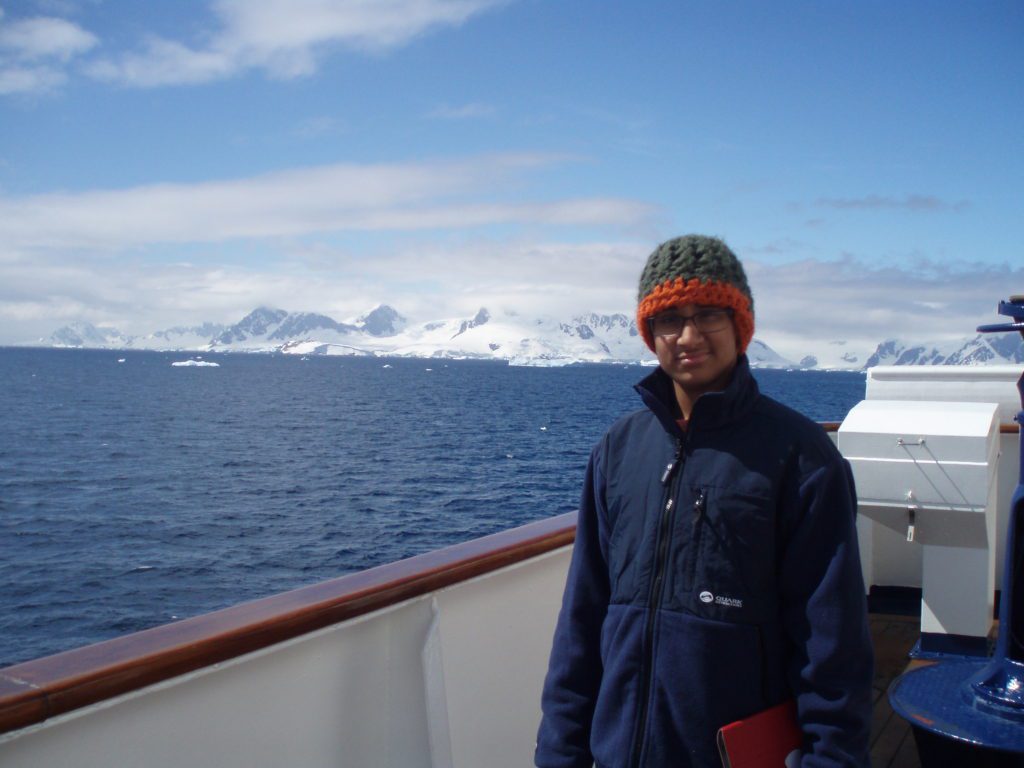 Man smiling in front of Antarctic landscape on boat