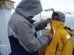 Man zipping up teenager's winter jacket