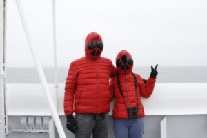 Man and woman in red full-body winter jackets