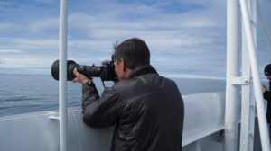 Man taking photograph with camera with long lens on boat