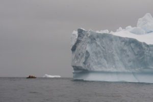 Large iceberg with small boat beside it