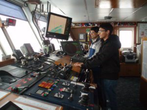Man and son standing in front of cruise ship controls