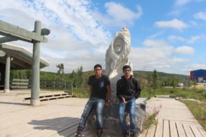 Teenagers posing in front of statue in Inuvik