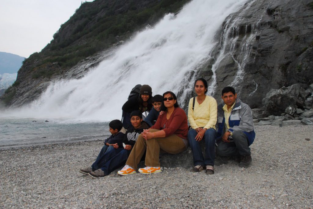 Family and friends sitting with Alaskan waterfall in background