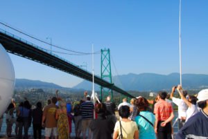 Passengers on cruise deck going under Vancouver bridge